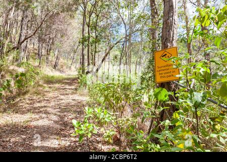 Ein Warnschild hing an dem Waldbaum und sagte - Überwachungskamera kann in diesem Park verwendet werden. Byron Bay, Australien Stockfoto