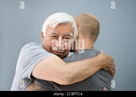 Sohn Umarmt Seinen Glücklichen Großvater Im Haus. Familie Zusammen Stockfoto