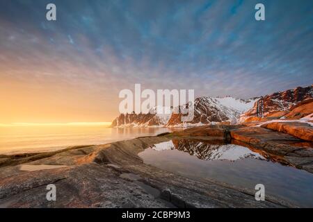 Felsiger Strand von Tungeneset, felsiger Gipfel Devils Zähne, Teufelszähne, Okshornan, in warmem Sonnenlicht, Stein Fjorde, Senja Insel, Troms, Norwegen Stockfoto