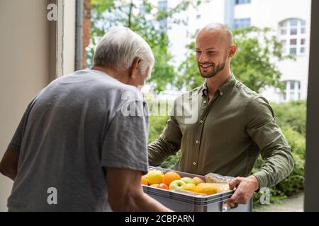 Hilfe Beim Einkaufen Von Lebensmitteln Für Älteren, Der Vor Der Tür Steht Stockfoto