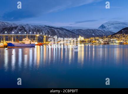 Blick über den Hafen und die Stadt mit Tromsobrua oder Tromso Brücke, hinten Tromsdalen Kirche, Arktisches Meer Kathedrale, Ishavskatdralen, in der Dämmerung Stockfoto