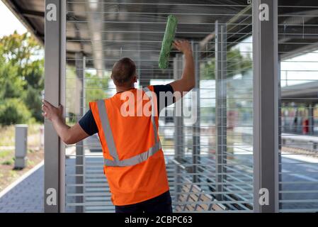 Mitarbeiter der Deutschen Bahn reinigt die Glasscheiben eines Wartebereichs auf einer Plattform, Magdeburg, Sachsen-Anhalt, Deutschland Stockfoto