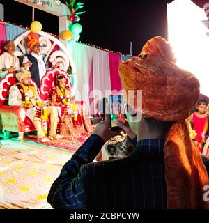 DISTRIKT KATNI, INDIEN - 23. Februar 2020: Ein indischer traditioneller Mann, der während der hinduistischen Hochzeitszeremonie auf das Bild von der Smartphone-Kamera klickt Stockfoto