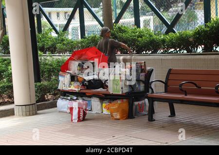 Eine obdachlose Frau in Hongkong hat all ihre Sachen auf einer Parkbank in einem Park in Sai Ying Pun im Westen Hongkongs. Stockfoto