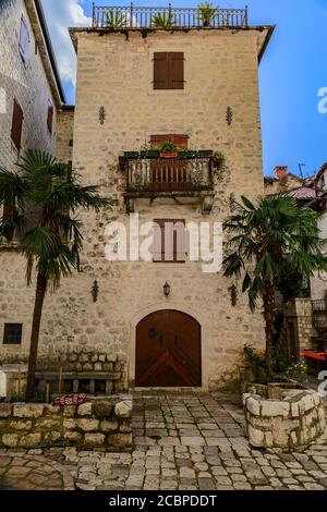 Altes Steinhaus mit einem Holztor auf einem malerischen Stadtplatz der gut erhaltenen mittelalterlichen Altstadt Kotor, Montenegro auf dem Balkan Stockfoto