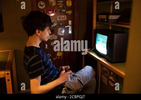 Ein fünfzehnjähriger Teenager spielt das ursprüngliche Nintendo-Spiel Mario Bros. Im Computerspiele Museum in Berlin. Stockfoto