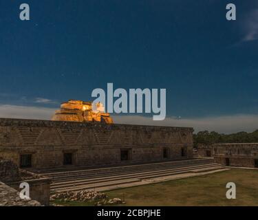 Die Pyramide des Magiers hinter dem Ostgebäude des Nonnenkackers ist sie in den prähispanischen Maya-Ruinen von Uxmal, Mexiko beleuchtet. Stockfoto