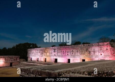 Das westliche Gebäude des Nunnery Quadrangle wird von farbigen Lichtern in den prähispanischen Maya-Ruinen von Uxmal, Mexiko, beleuchtet. Stockfoto