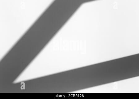 Schattenüberlagerungseffekt für das Foto. Geometrischer Schatten aus einem Fenster oder einer Tür an einer weißen sauberen Wand bei klarem Wetter. Geometrische Komposition Schatten Stockfoto