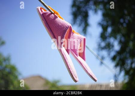 Lila weibliche Hausschuhe werden auf einer Wäscheleine in einem getrocknet Sommergarten Stockfoto
