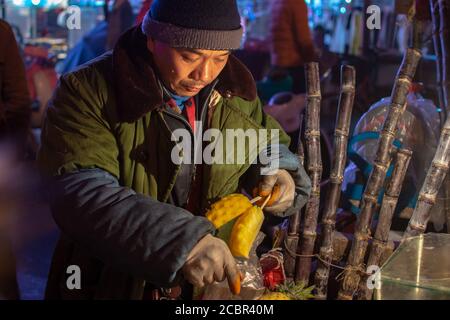 Luoyang, Provinz Henan / China - 3. Januar 2016: Mann schneidet und verkauft frische Ananasscheiben auf der Straße Lebensmittel Obststand in Luoyang, China Stockfoto