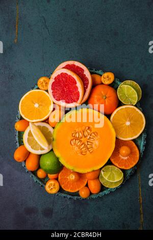 Flaches Lay-Layout von Zitrusfrüchten und anderen Sommerfrüchten auf grünem Hintergrund. Gesunde Ernährung Konzept. Stockfoto