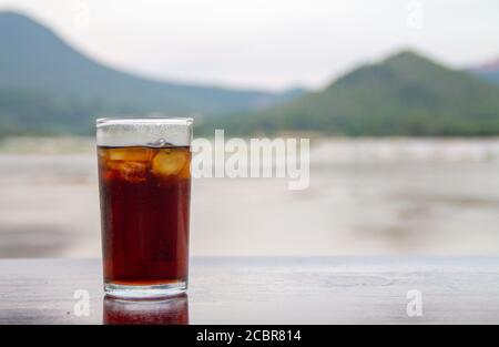 Cola im Glas auf Tisch mit Berg- und Flusshintergrund Stockfoto