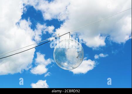 Außenlampe bei Tageslicht - durchsichtige Glaskugel mit Glühbirne ist auf der Schnur. Blauer Himmel mit weißen Wolken im Hintergrund. Leerzeichen um die LIGH kopieren Stockfoto