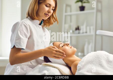 Gesichtshautpflege Verfahren. Kosmetikerin macht eine Massage mit dem Gesicht einer Frau in einer Kosmetikklinik Stockfoto