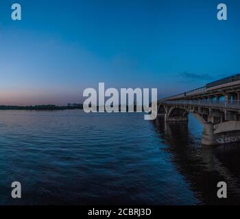 Blick auf die U-Bahn-Brücke und den Dnipro-Fluss bei Sonnenuntergang. Kiew, Ukraine Stockfoto