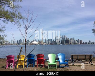 Farbenfrohe Stühle im Centre Island mit Downtown Toronto im Hintergrund. Stockfoto