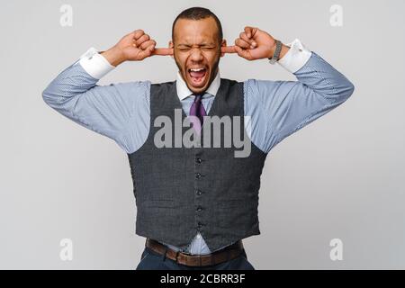 Junger afroamerikanischer Mann, der seine Hände hoch hält Ohren versuchen, alle Stimmen, die er hört und stummzuschalten Schreiend Stockfoto