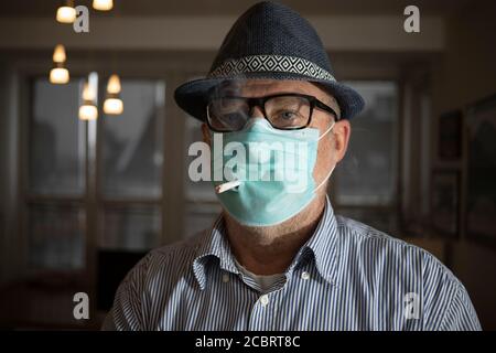 Doppelter Schutz - Porträt eines Mannes mit Gesichtsmaske Beim Rauchen einer Zigarette Stockfoto