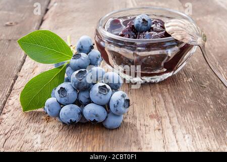 Heidelbeermarmelade und Beeren aus der Nähe auf einem alten Holztisch Stockfoto
