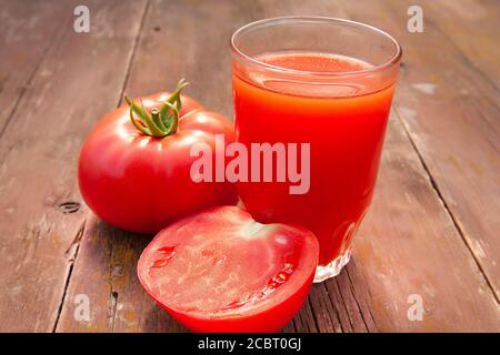 Tomatensaft im Glas und Tomaten auf einem alten Holztisch Nahaufnahme Stockfoto