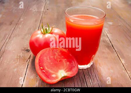 Tomatensaft im Glas und Tomaten auf einem alten Holztisch Nahaufnahme Stockfoto