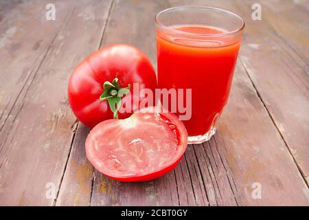 Tomatensaft im Glas und Tomaten auf einem alten Holztisch Nahaufnahme Stockfoto