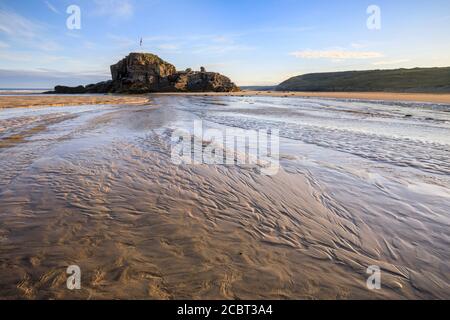 Chapel Rock am Perranporth Beach in Cornwall, aufgenommen an einem Morgen Mitte Juli mit Sandmustern als Vordergrund-Interesse. Stockfoto