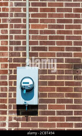 Vertikale Aufnahme eines elektrischen Zählers auf einer alten roten Ziegelwand. Speicherplatz kopieren. Stockfoto