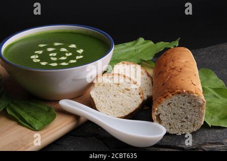 Spinatcremesuppe in einer Schüssel mit frischem Brot und Creme Stockfoto