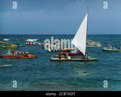 Aus den anderen, in smaragdgrünen Gewässern vor dem Strand von Porto de Galinhas verankerten, gehisst ein Floß weißer Segel. Stockfoto