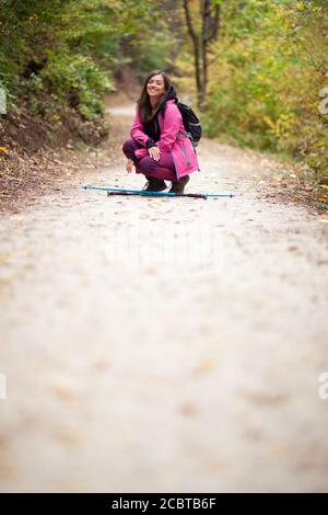 Hiker Mädchen hocken auf einem Weg in den Bergen. Rucksacktourist mit rosa Jacke in einem Wald. Gesunder Fitness-Lebensstil im Freien. Stockfoto