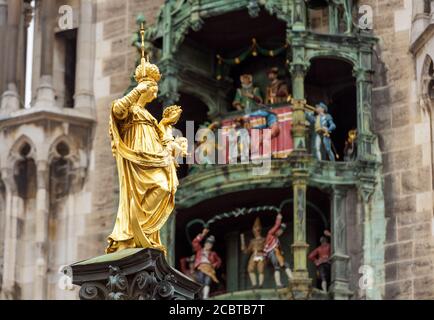 Statue der Jungfrau Maria in Nahaufnahme auf dem Marienplatz, München, Deutschland. Dieses Hotel ist ein Wahrzeichen Münchens. Goldene Skulptur auf Mariensaule Säule auf Stockfoto