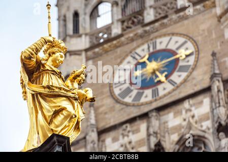 Statue der Jungfrau Maria in Nahaufnahme auf dem Marienplatz, München, Deutschland. Dieses Hotel ist ein Wahrzeichen Münchens. Goldene Skulptur auf Mariensaule Säule auf Stockfoto