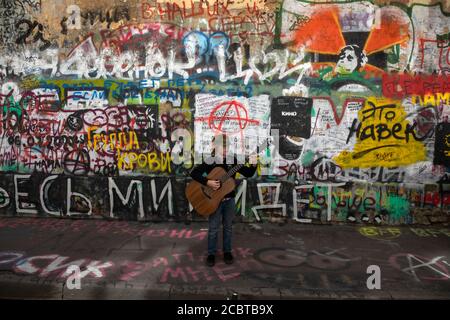 Moskau, Russland. 15. August 2020 EIN kleiner Fan von Viktor Tsoi singt ein Lied mit Gitarre auf dem Hintergrund der Tsoi-Mauer in der Arbat-Straße in Moskau am 30. Todestag des Sängers, Russland. Die Tsoi Wall ist eine mit Graffiti bedeckte Wand in Moskau, die dem Musiker Viktor Tsoi und seiner Band Kino gewidmet ist Stockfoto