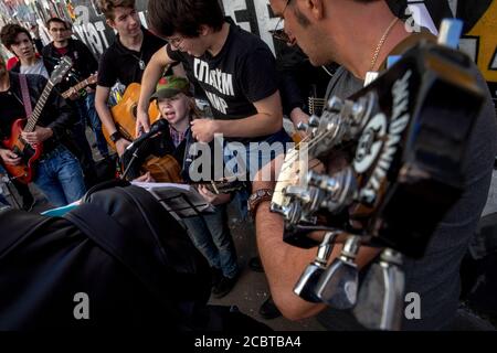 Moskau, Russland. 15. August 2020 EIN kleiner Fan von Viktor Tsoi singt ein Lied mit Gitarre auf dem Hintergrund der Tsoi-Mauer in der Arbat-Straße in Moskau am 30. Todestag des Sängers, Russland. Die Tsoi Wall ist eine mit Graffiti bedeckte Wand in Moskau, die dem Musiker Viktor Tsoi und seiner Band Kino gewidmet ist Stockfoto