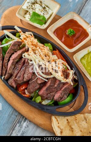 Beef Fajitas mit bunten Paprika in Pfanne und Saucen Stockfoto