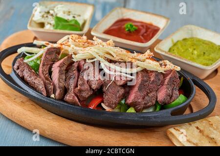 Beef Fajitas mit bunten Paprika in Pfanne und Saucen Stockfoto