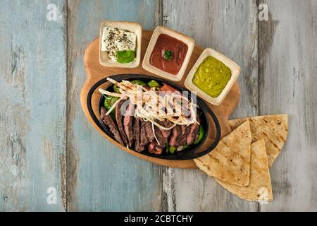 Beef Fajitas mit bunten Paprika in Pfanne und Saucen Stockfoto