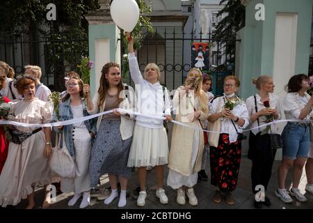 Moskau, Russland. 15. August 2020 Frauen halten Blumen in der Hand, während sich Menschen, einige von ihnen ethnische Weißrussen und weiße Kleidung, vor der belarussischen Botschaft in Moskau, Russland, zu einer Kundgebung gegen die Ergebnisse der belarussischen Präsidentschaftswahl versammeln. Rund 400 Menschen, meist Frauen, stehen in der Maroseyka-Straße in der Nähe der belarussischen Botschaft in Solidarität mit den Demonstranten, die bei den jüngsten Kundgebungen in Belarus verletzt wurden Stockfoto