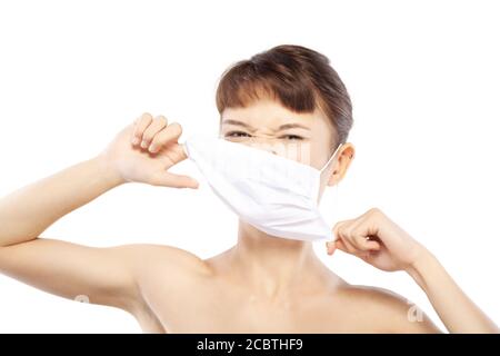 Wütend traurig Mädchen ziehen ihre medizinische Gesichtsmaske zum Schutz vor Corona-Virus, Polution oder Staub. Quarantäne- und Selbstisolierungskonzept. Stockfoto