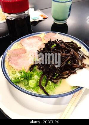 Nahaufnahme von japanischem gegrilltem Char siu-Schweinefleisch-Ramen-Nudeln in Schweineknochenbrühe und gekrönt mit Frühlingszwiebeln.Nishijin Shopping District in Fukuoka. Stockfoto