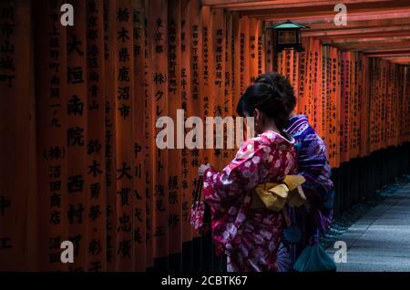 Frauen in traditionellen japanischen Kimonos wandern am Fushimi Inari Schrein in Kyoto, Japan. Das Highlight des Schreins sind die Reihen der Torii-Tore. Stockfoto