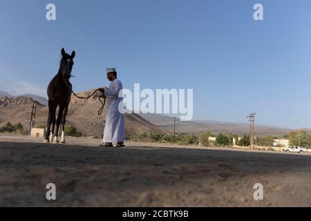 Ein omani Mann trägt traditionelle Mütze Training sein Pferd Stockfoto