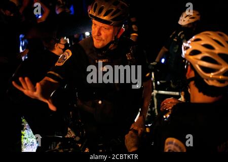 Während eines Protestes gegen systemischen Rassismus und Polizeigewalt in Washington, DC, am verregneten 15 2020. August inmitten der Coronavirus-Pandemie, protestierte ein Polizist in einem angespannten Moment gegen Demonstranten, während viele Demonstranten darauf bestanden, dass der Polizist eine Maske auflegte. Nach einem Zwischenfall Anfang der Woche, bei dem die Washington Metropolitan Police mehr als 40 Demonstranten während eines angeblichen Aufruhrs festnahm, von dem Zeugen und Berichte sagen, dass es sich um eine überwiegend friedliche Demonstration handelte, Demonstranten - darunter viele, die vor kurzem ohne Anklage aus dem Gefängnis entlassen worden waren - marschierten erneut für eine elfte Woche durch die Stadt. Stockfoto