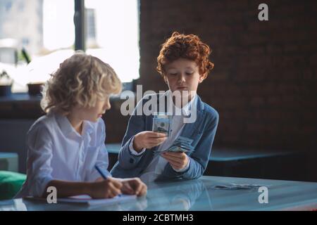 Zwei Jungs, die Geld zählen und beschäftigt sind Stockfoto