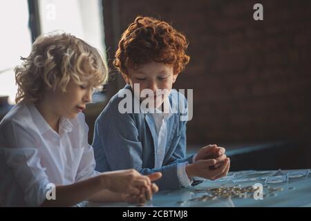 Zwei Jungen zählen Münzen und suchen beschäftigt Stockfoto