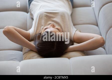 Heitere junge Frau ruht sich zu Hause auf der weichen Couch aus Stockfoto