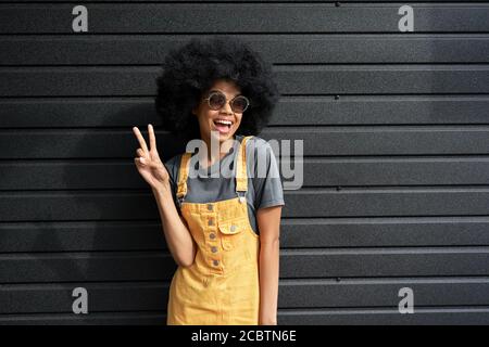 Happy African teen Hipster Mädchen tragen stilvolle Gläser stehen gegen schwarze Wand. Stockfoto