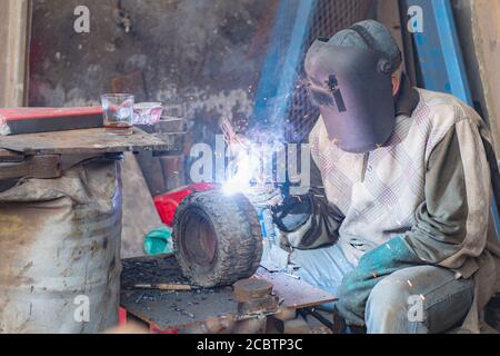 Ein Schweißer, der in EINER schlechten Schweißwerkstatt arbeitet Stockfoto